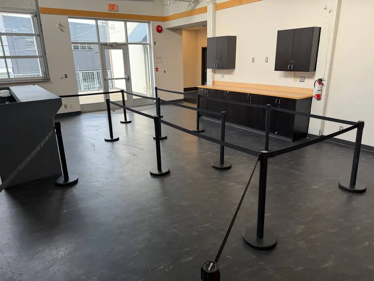 Black belt stanchions run in a rectangle across a dark floor in front of a service counter, closing off the area in front of it.