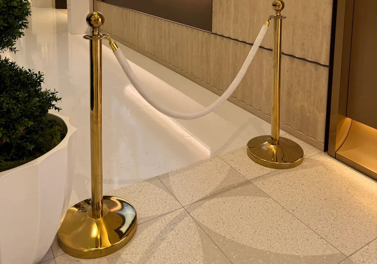 Two gold rope posts carrying a white rope across a polished retail entrance