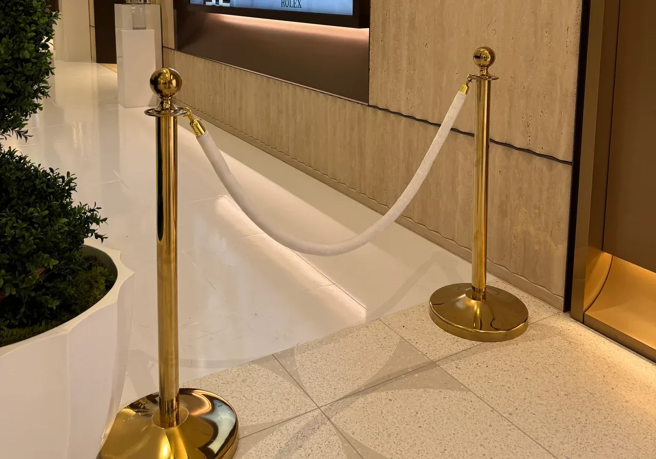 Two gold rope posts carrying a white rope across a polished retail entrance