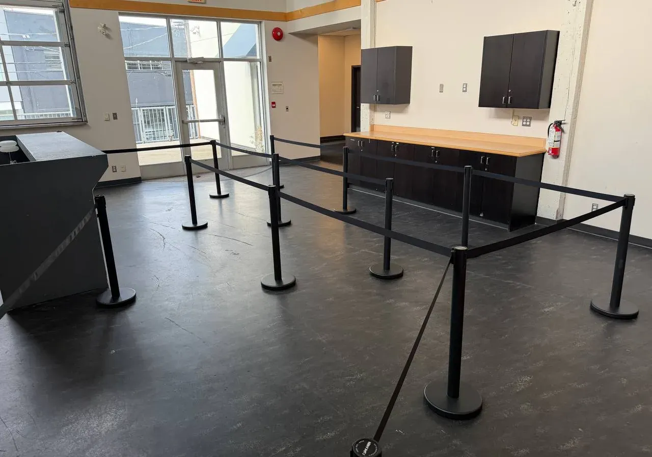 Black belt stanchions set out as queue lanes across the floor of an empty indoor venue