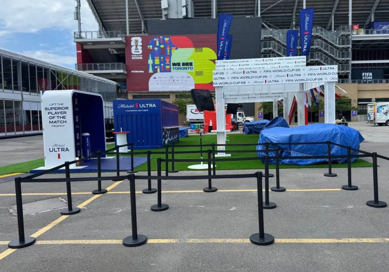 Black belt stanchions set out as holding pens across a stadium plaza on a match day